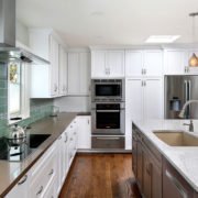 A Mountain View kitchen offers a chic, beachy feel with white cabinetry and a seafoam green backsplash.