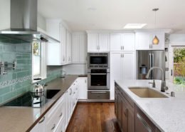 A Mountain View kitchen offers a chic, beachy feel with white cabinetry and a seafoam green backsplash.