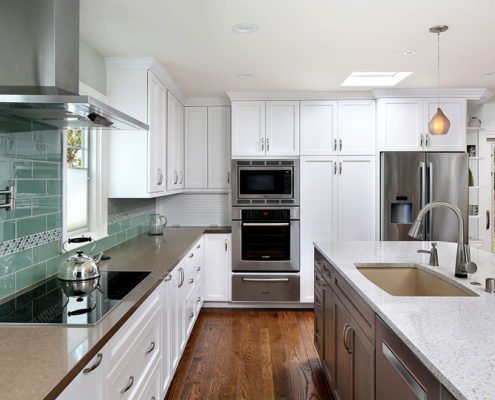 A Mountain View kitchen offers a chic, beachy feel with white cabinetry and a seafoam green backsplash.