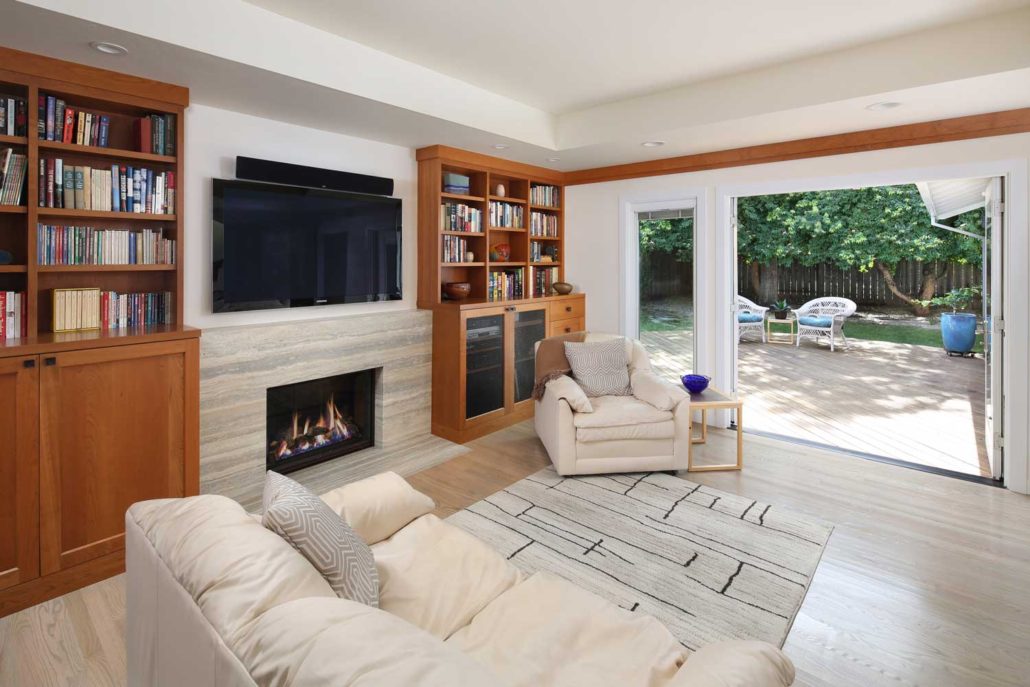 Indoor-outdoor living with built-in bookshelves and fireplace