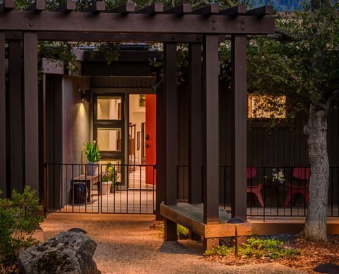 A pergola with a bench seat establishes an entryway to this Portola Valley home.