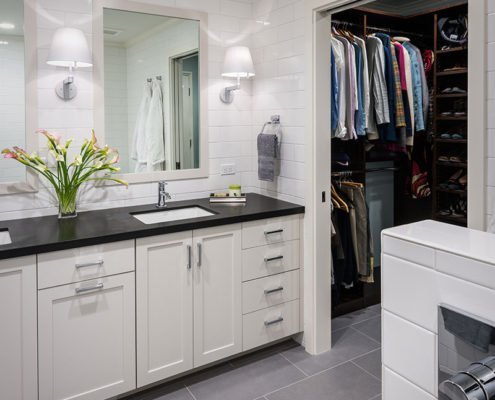 A monochromatic universal design bathroom has a walk-in closet with an extra wide doorway, accessible for wheelchair users.