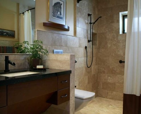 A universal design bathroom with a curbless shower with a curved curtain rod, a tankless wall-mounted toilet, and wooden roll-under vanity.
