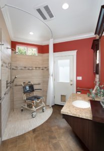 A universal design bathroom features a corner curbless shower with a shower wheelchair.