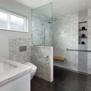 A modern, gray universal design bathroom features a curbless shower and tile details.