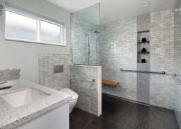 A modern, gray universal design bathroom features a curbless shower and tile details.