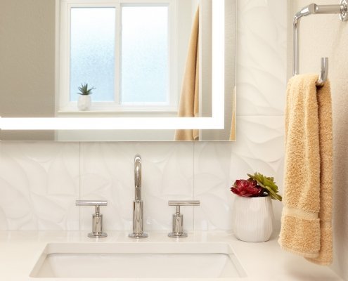 A modern, neutral bathroom in Mountain View adds a touch of interest with a textured tile wall.