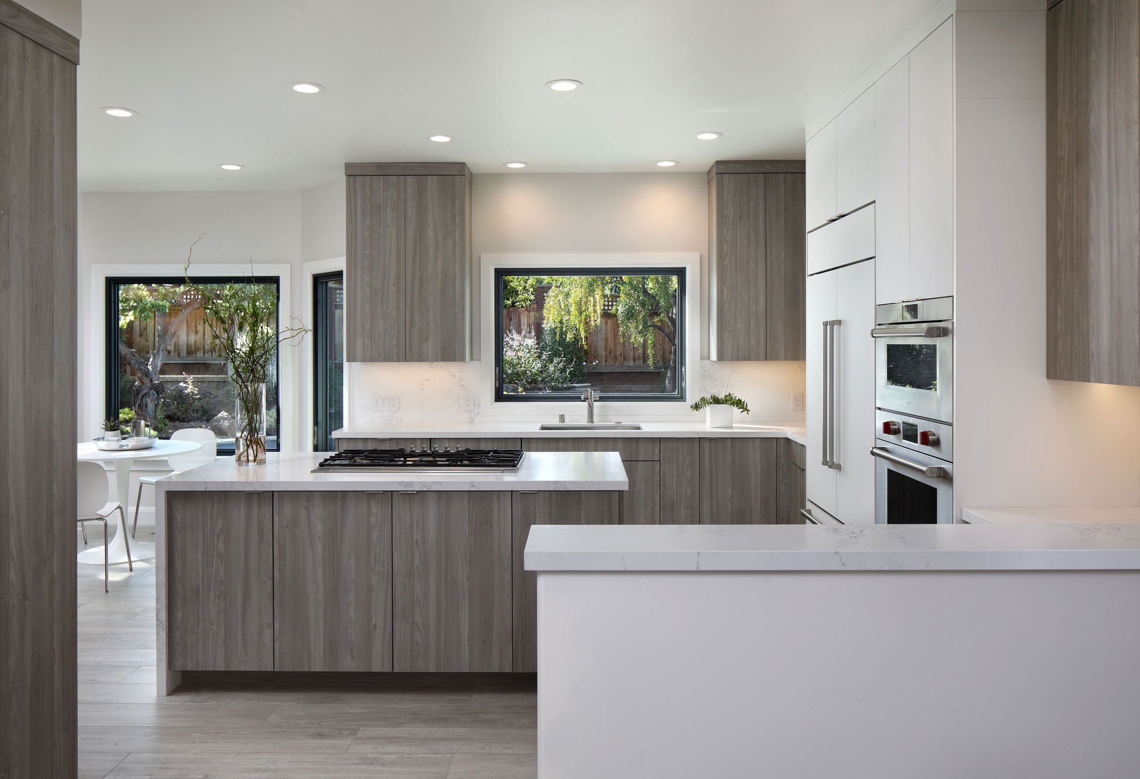 A sleek, neutral kitchen offers views of the backyard from the sink and breakfast nook.