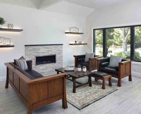 A stone surround fireplace and illuminated shelves are the focal points of this sleek, neutral living room.