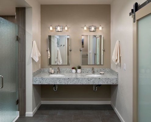 A contemporary universal design bathroom features a dual, roll-under vanity and a curbless shower with frosted glass doors.