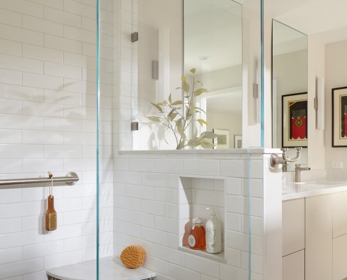 This shower's pony wall provides a storage nook next to a stone-accented corner seat.