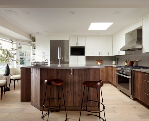 A modern kitchen in Los Altos offers contrast between moody wooden lower cabinets and bright white uppers.