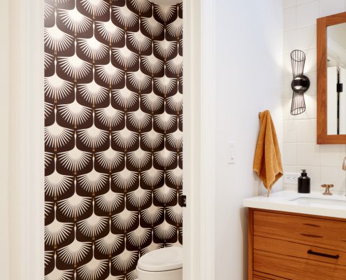 A water closet in San Jose features small, hexagonal floor tiles and a large, graphic wallpaper.