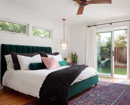 A modern, cozy bedroom in San Jose features a sliding door to the backyard and drop pendant lighting.