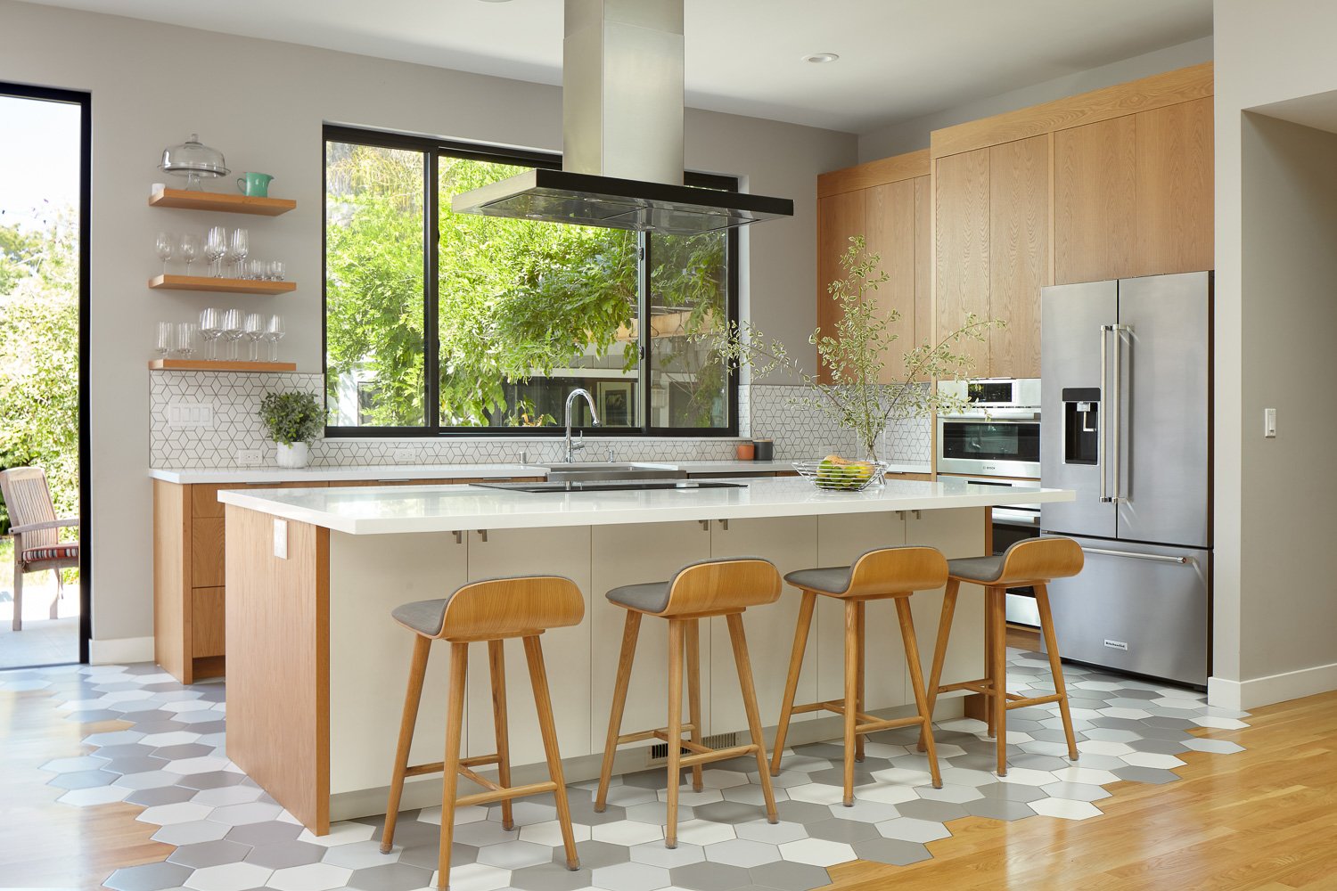 A modern kitchen in San Jose with geometric tile floors and backsplash, wood cabinetry, and stainless steel appliances.