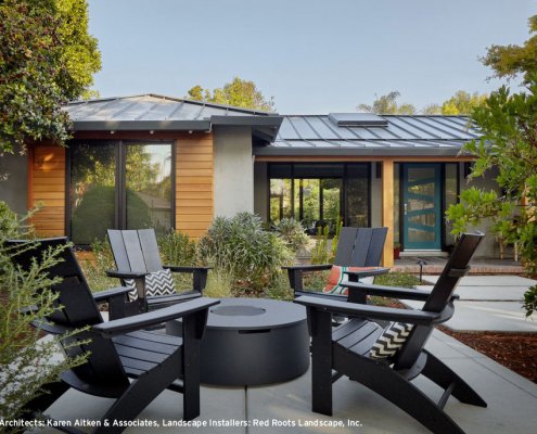Sleek black Adirondack chairs surround a modern black firepit in the backyard of a San Jose home.
